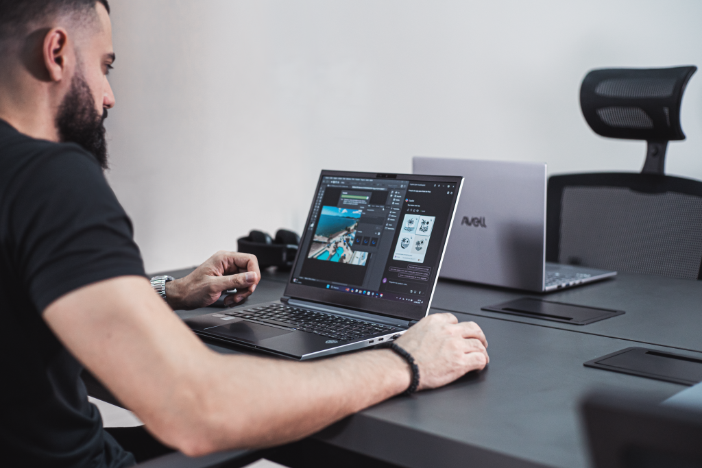 Homem usando notebook para estudante Avell em ambiente moderno, ideal para design gráfico, estudos e multitarefas em 2025.