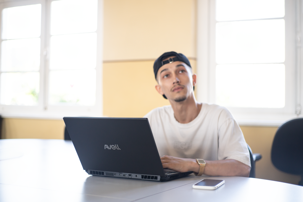 Homem usando notebook Avell HYB A50i em ambiente corporativo, destacando desempenho e design moderno da linha Avell 