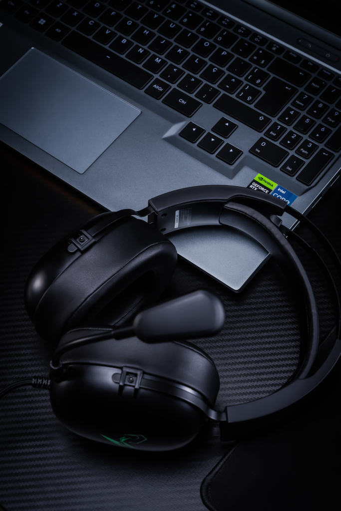 Headset gamer Avell com microfone ajustável ao lado de notebook Avell com placa gráfica NVIDIA GeForce RTX, ideal para jogos e produtividade