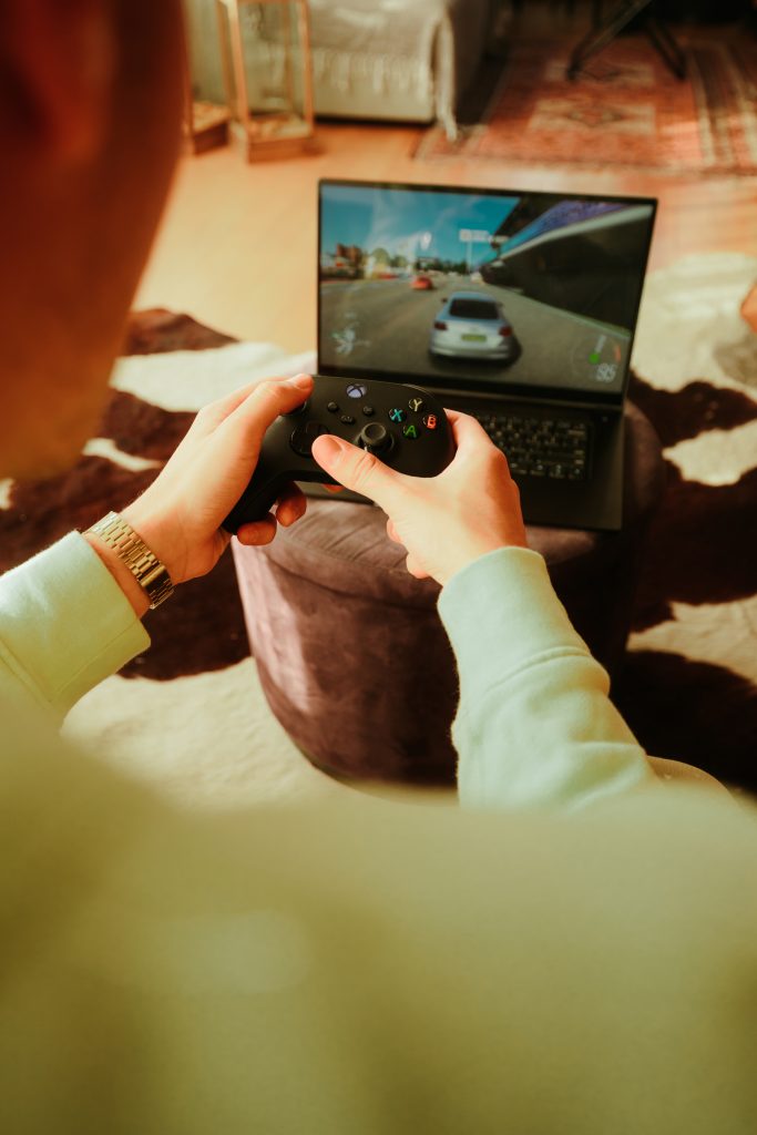 Pessoa jogando em um notebook gamer com controle de Xbox, ideal para jogos com alto desempenho gráfico

