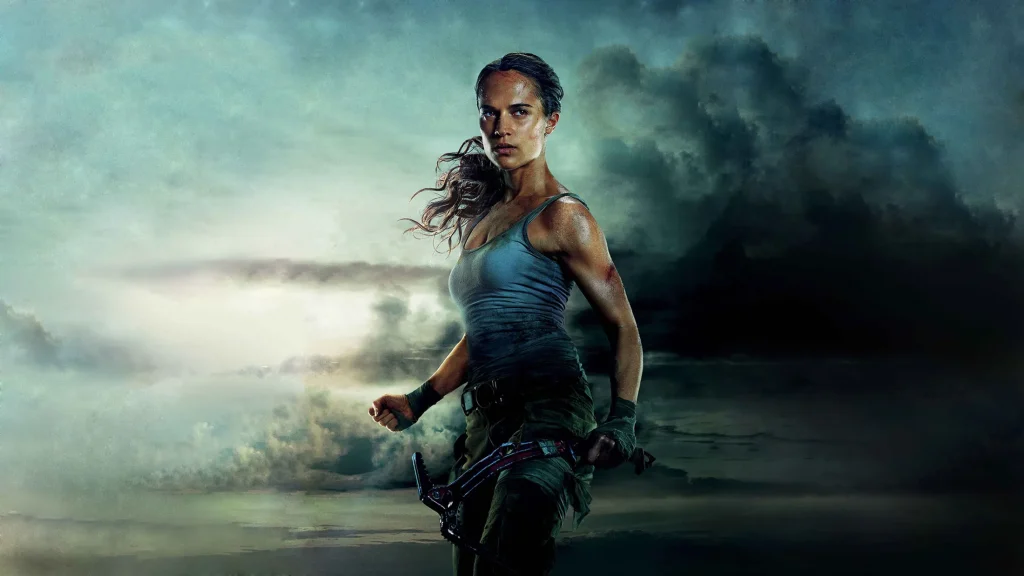 Lara Croft armada com arco em cena promocional do filme Tomb Raider: A Origem, com céu nublado ao fundo e expressão determinada.
