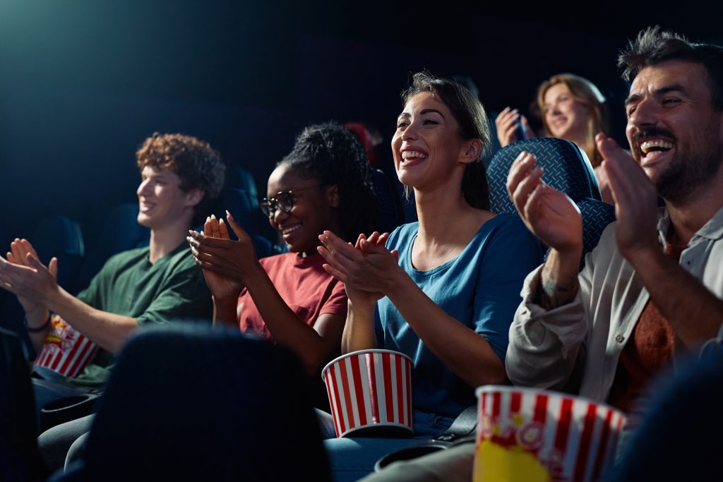 Público aplaudindo no cinema após assistir a adaptações de jogos que ganharam as telas, demonstrando entusiasmo com as produções inspiradas em videogames.